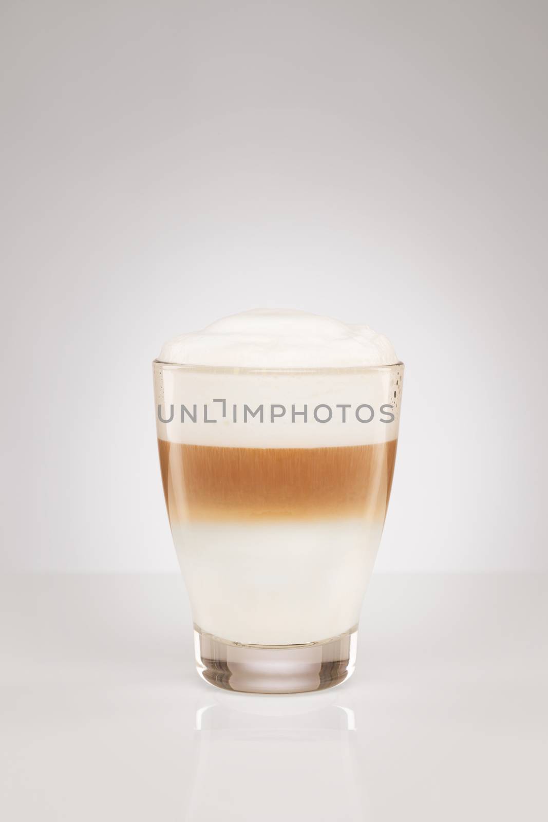 latte macchiato in a small glass on gray background