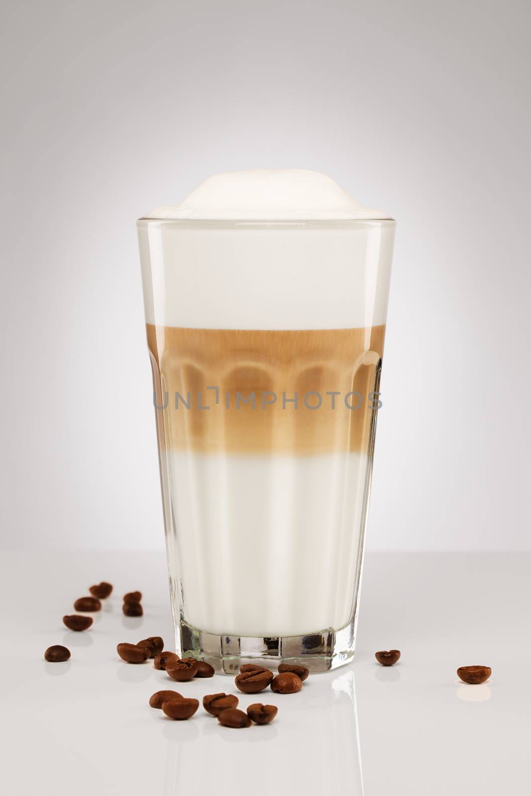 one original latte macchiato with coffee beans on gray background