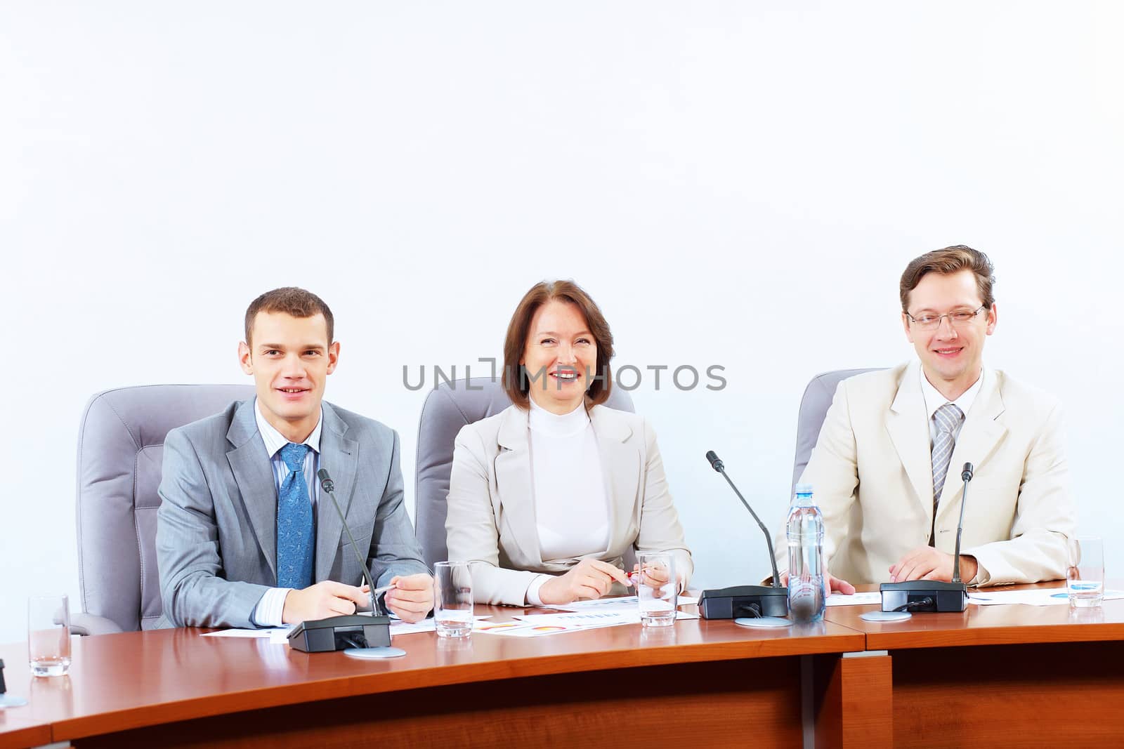 Image of three businesspeople sitting at table at conference