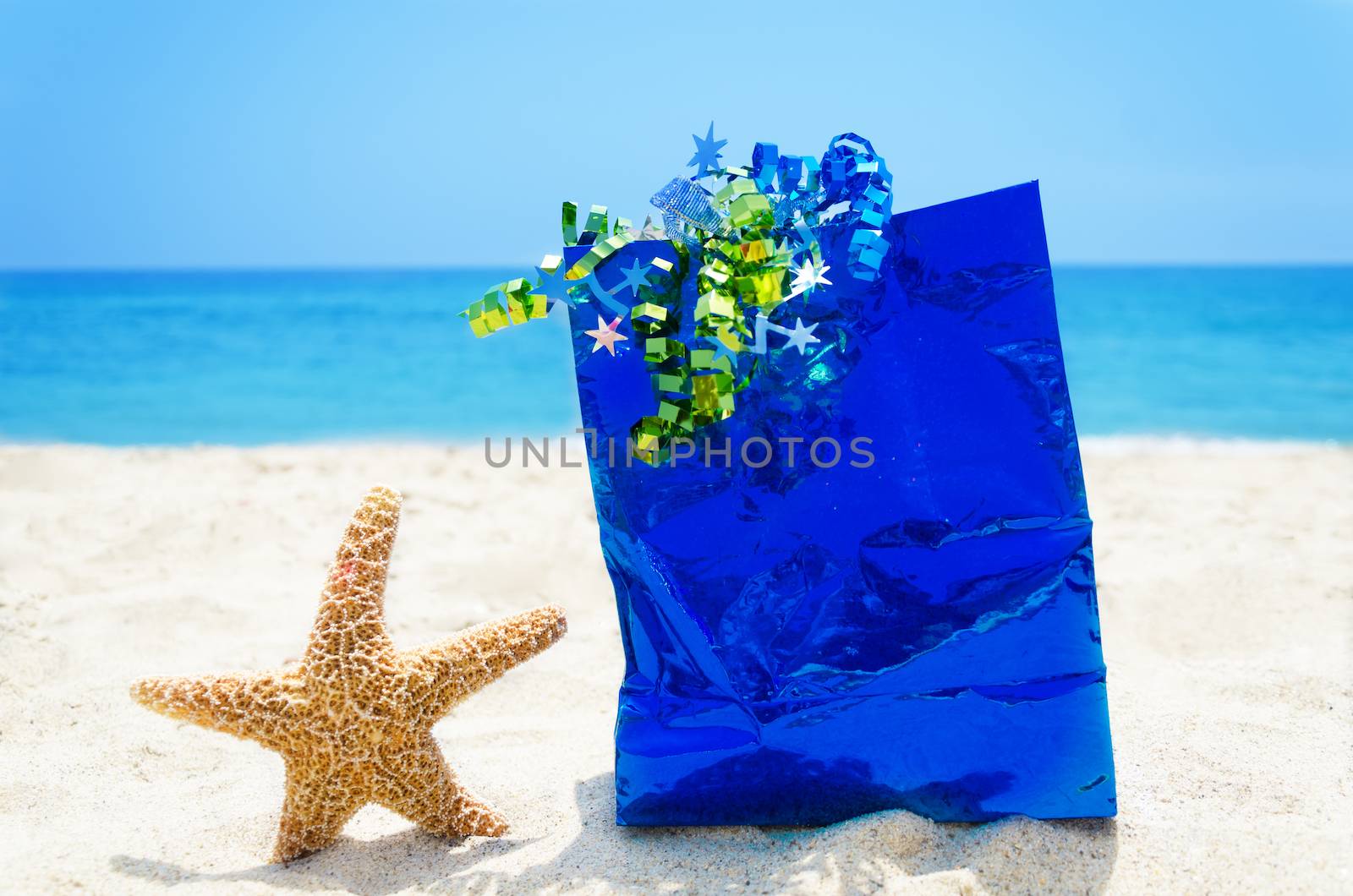 Starfish with blue gift bag on sandy beach in sunny day- holiday concept