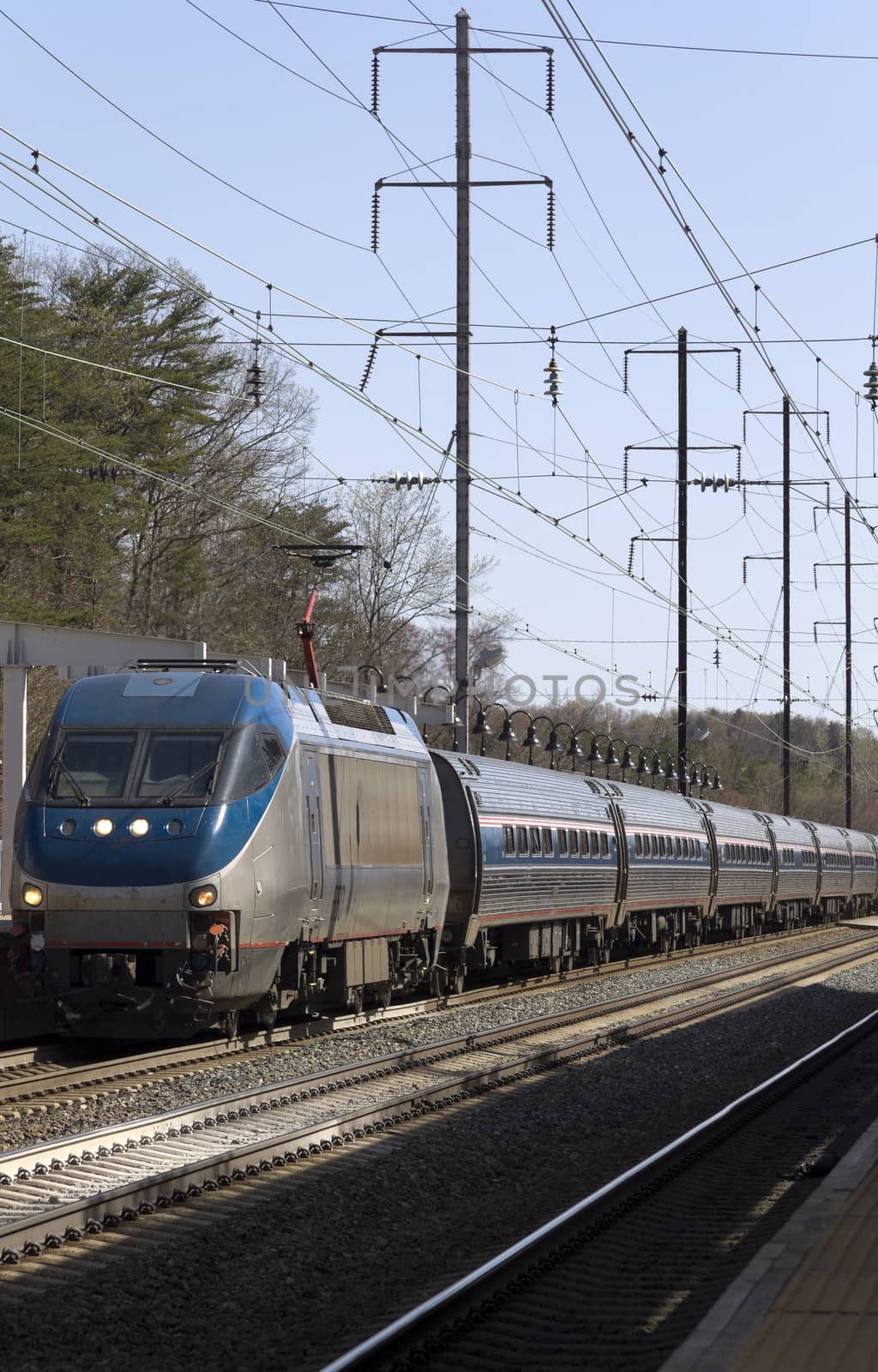 An electric train pulling into a station on rail road tracks