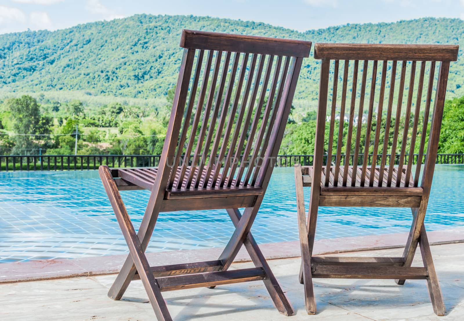 Wooden chair near the pool. With a mountain backdrop.