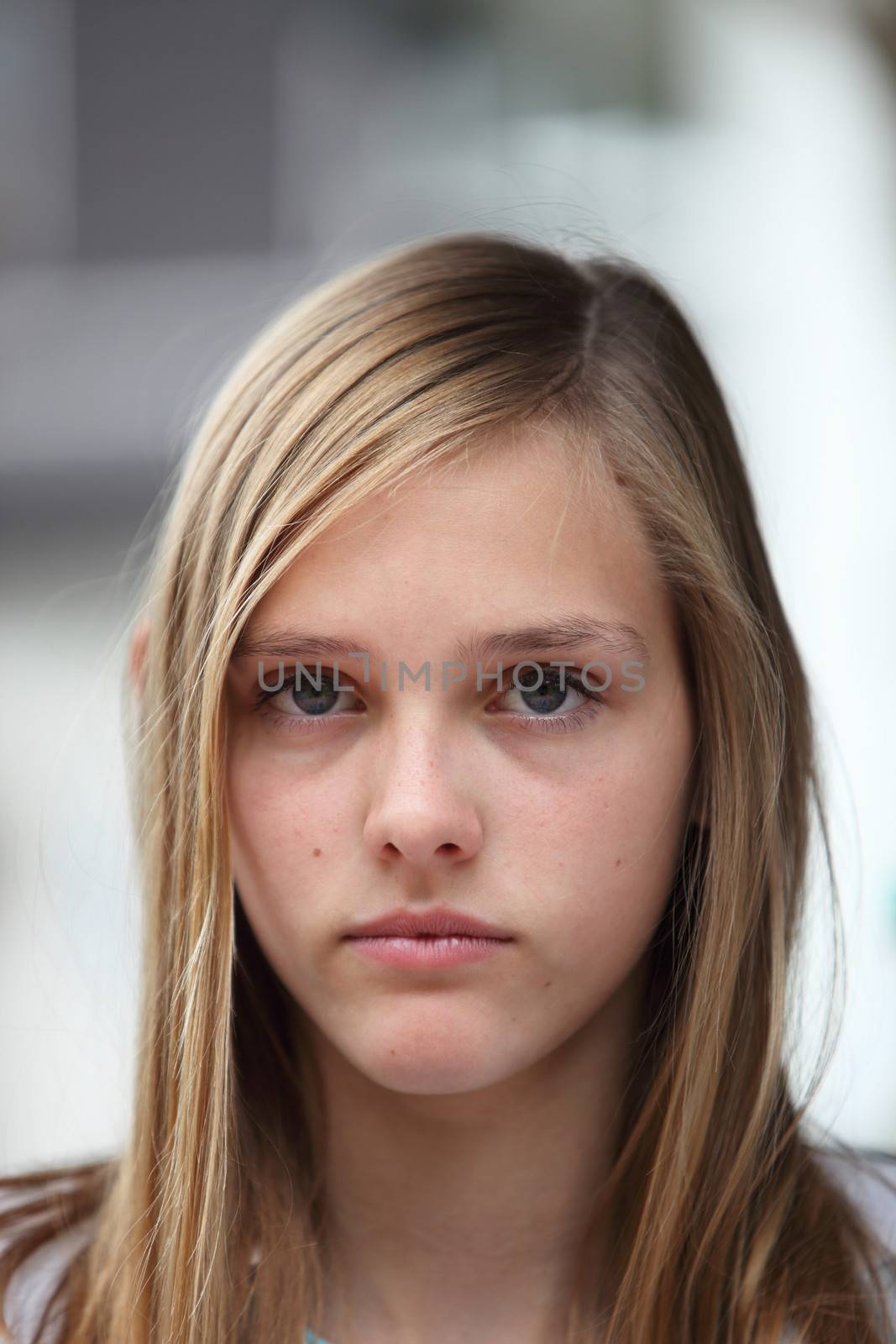 Young teenage girl with a serious expression and long blond hair looking directly at the camera