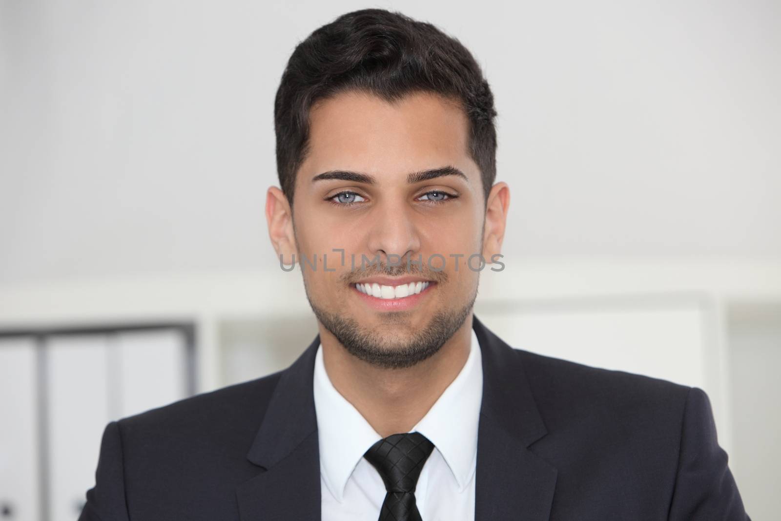 Head and shoulders portrait of a smiling friendly businessman in his office looking directly at the camera