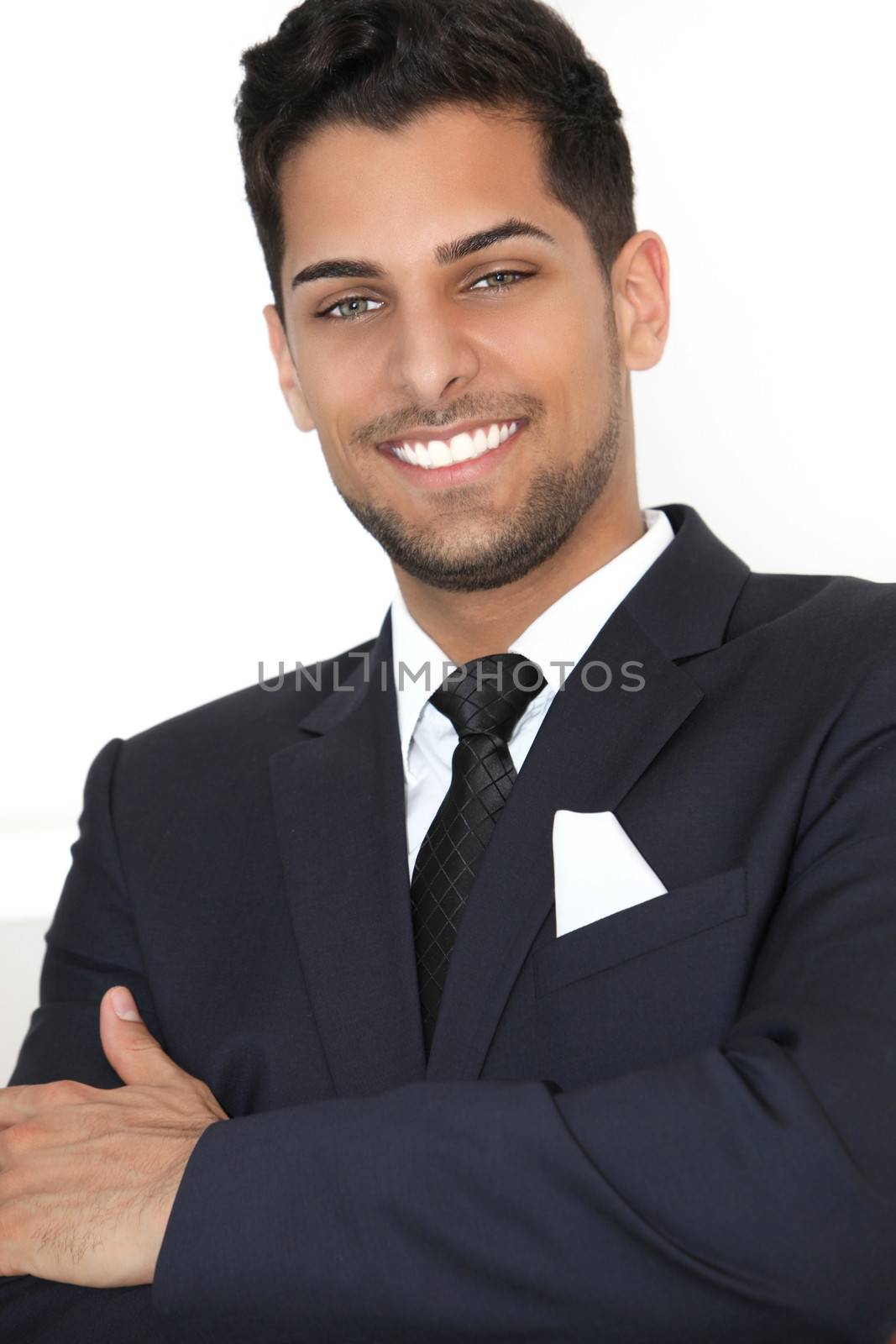 Handsome confident man with a lovely smile dressed in a stylish suit standing with his arms folded isolated on white
