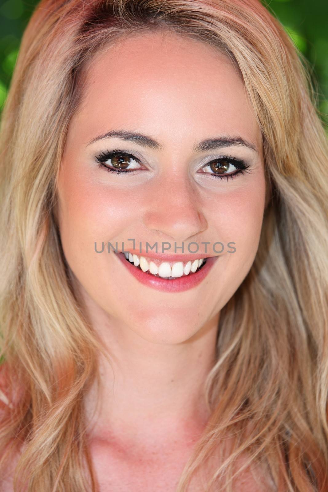 Close up headshot portrait of a beautiful blond woman with a lovely smile and subtle makeup