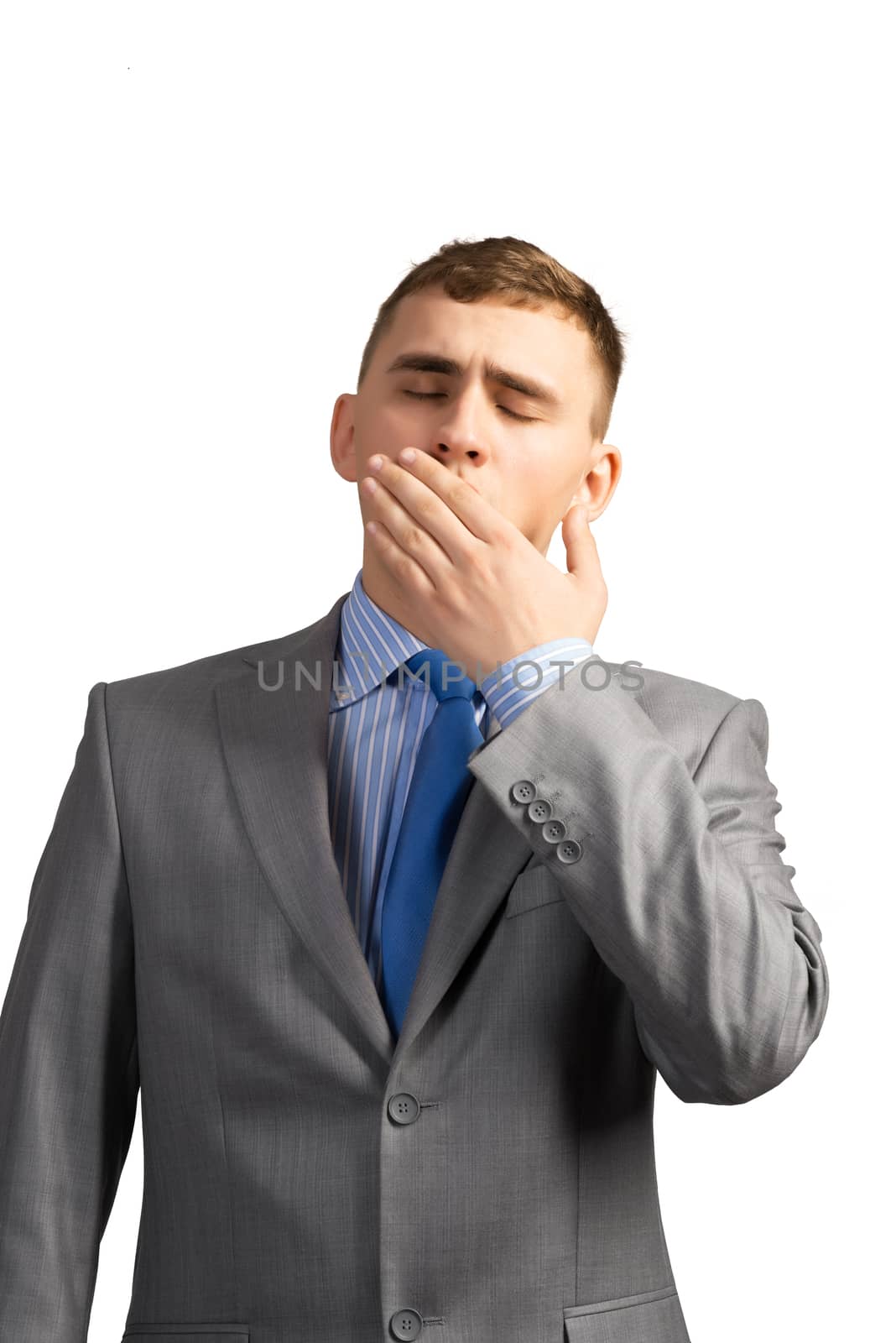 Portrait of a tired young businessman yawning behind her hand, isolated on white background