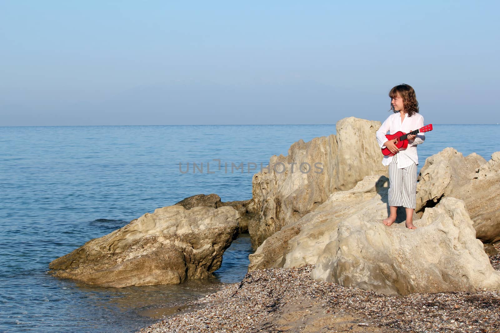 little girl with guitar standing on a rock by goce