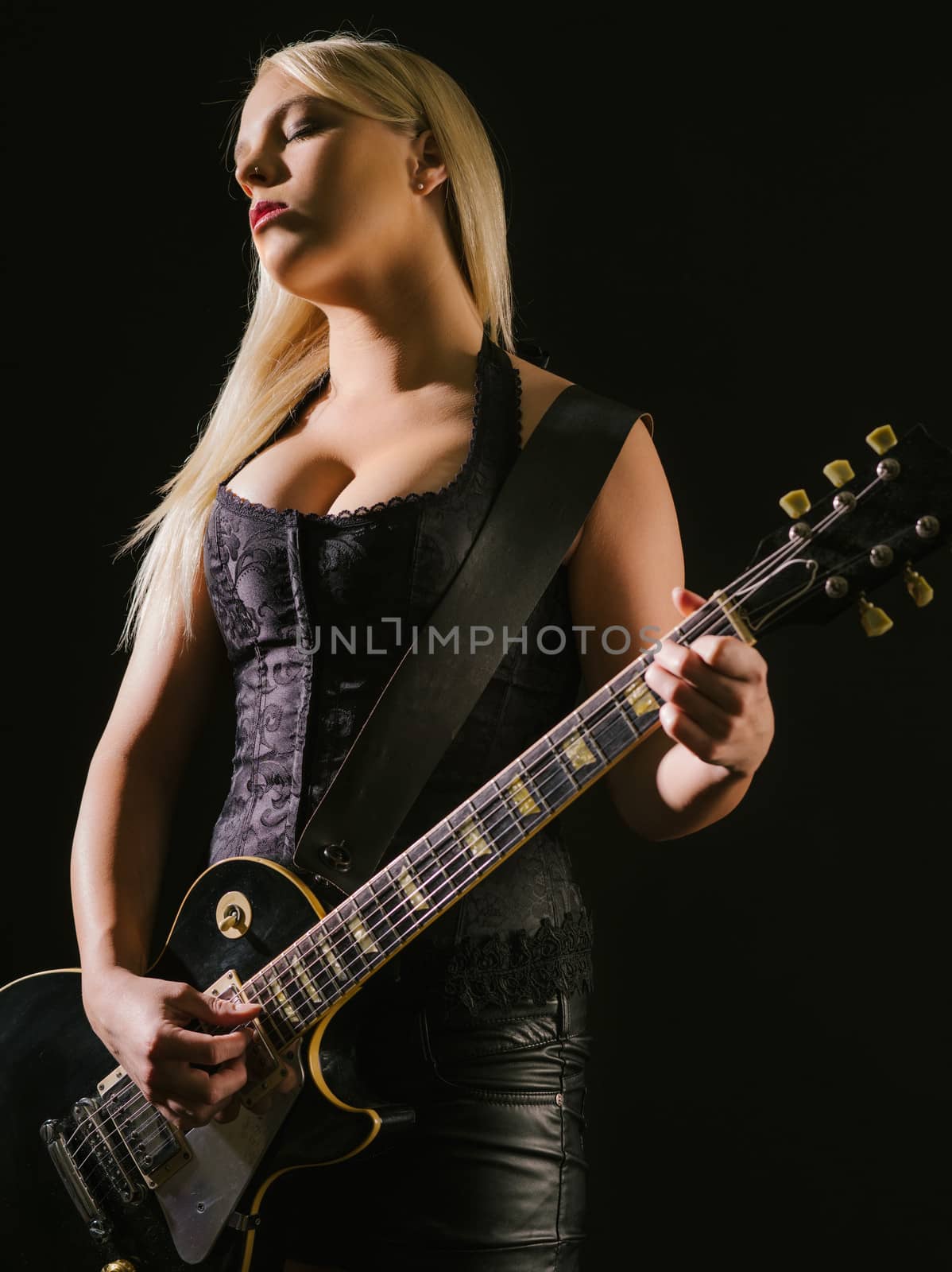 Photo of a sexy blond female playing a black electric guitar.