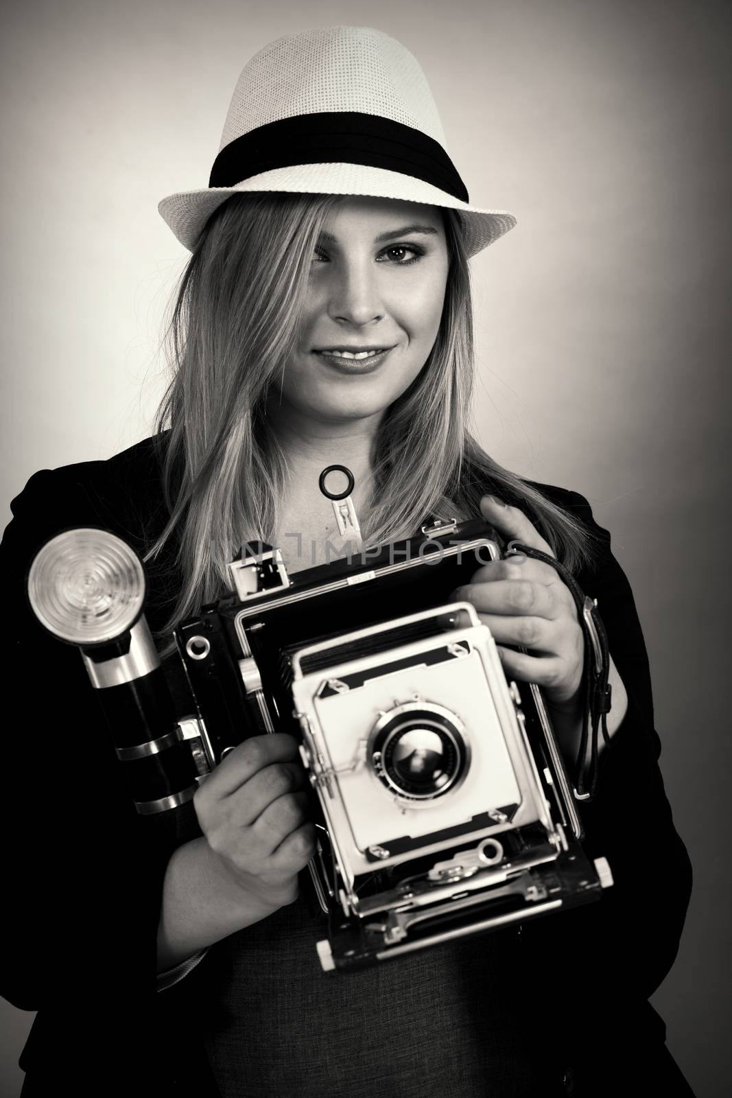 Photo of a beautiful young blond woman holding a vintage 4x5 film camera.