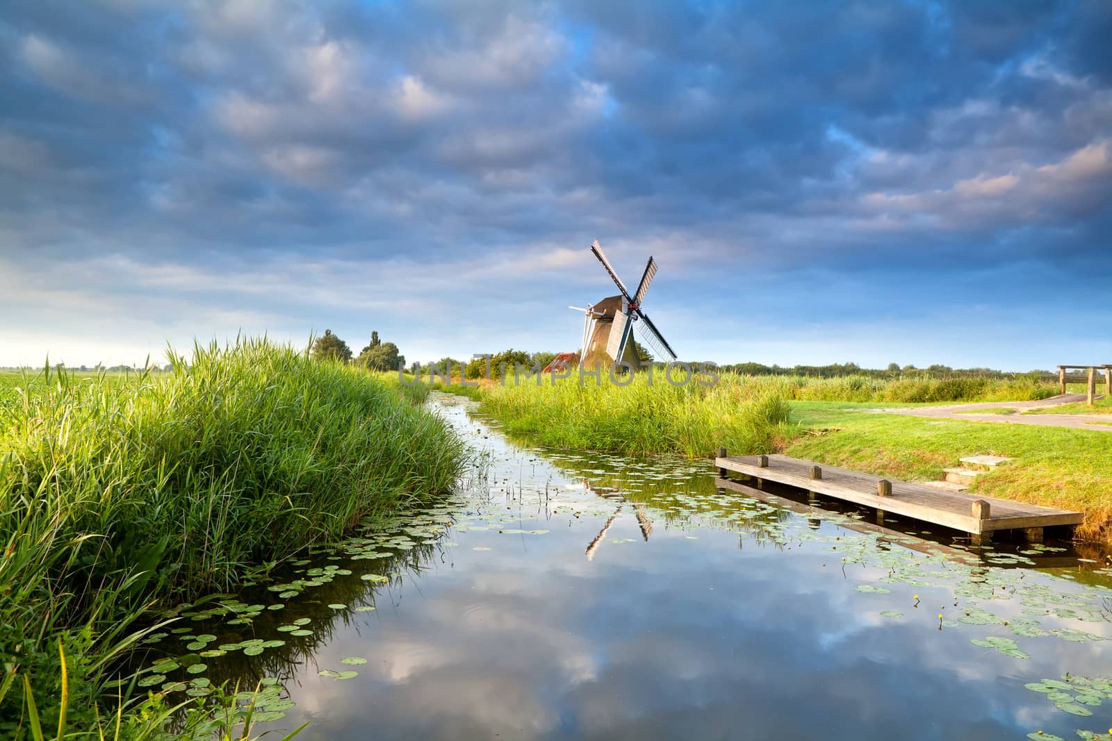 Dutch windmill and blue morning sky reflected in river