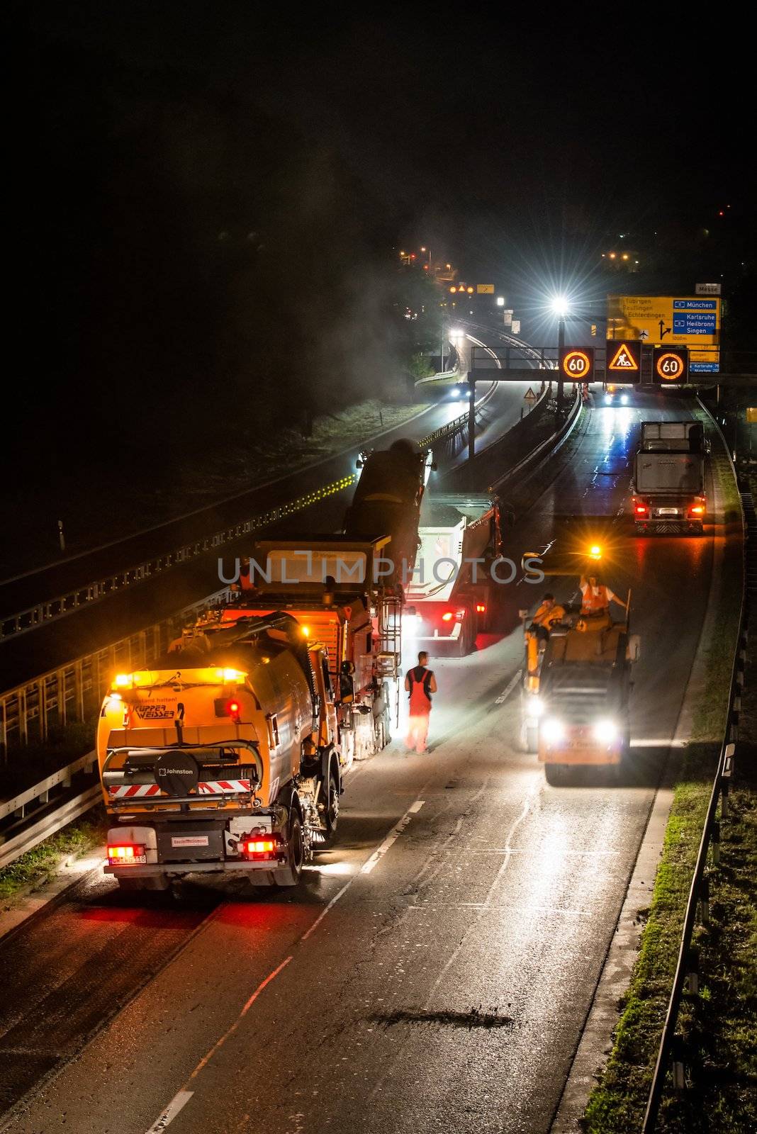 STUTTGART, GERMANY - AUGUST 16 ,2013: Workers removing asphalt on a public interstate (B27) using heavy machinery during holiday season on the evening of August 16, 2013 in Stuttgart, Germany.