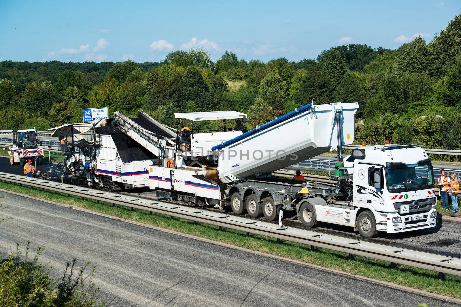 STUTTGART, GERMANY - AUGUST 17,2013: Workers laying asphalt on a public interstate (B27) using heavy machinery during holiday season on August 17, 2013 in Stuttgart, Germany.