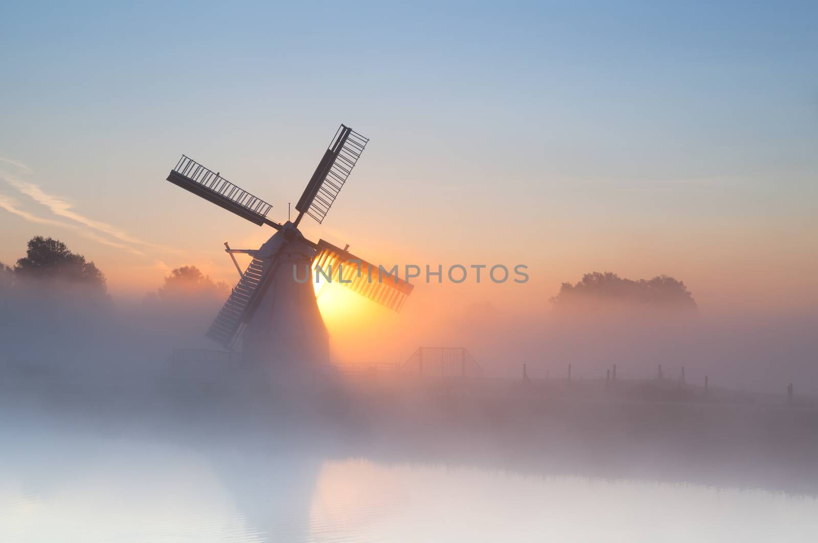 Dutch windmill in dense fog at sunrise