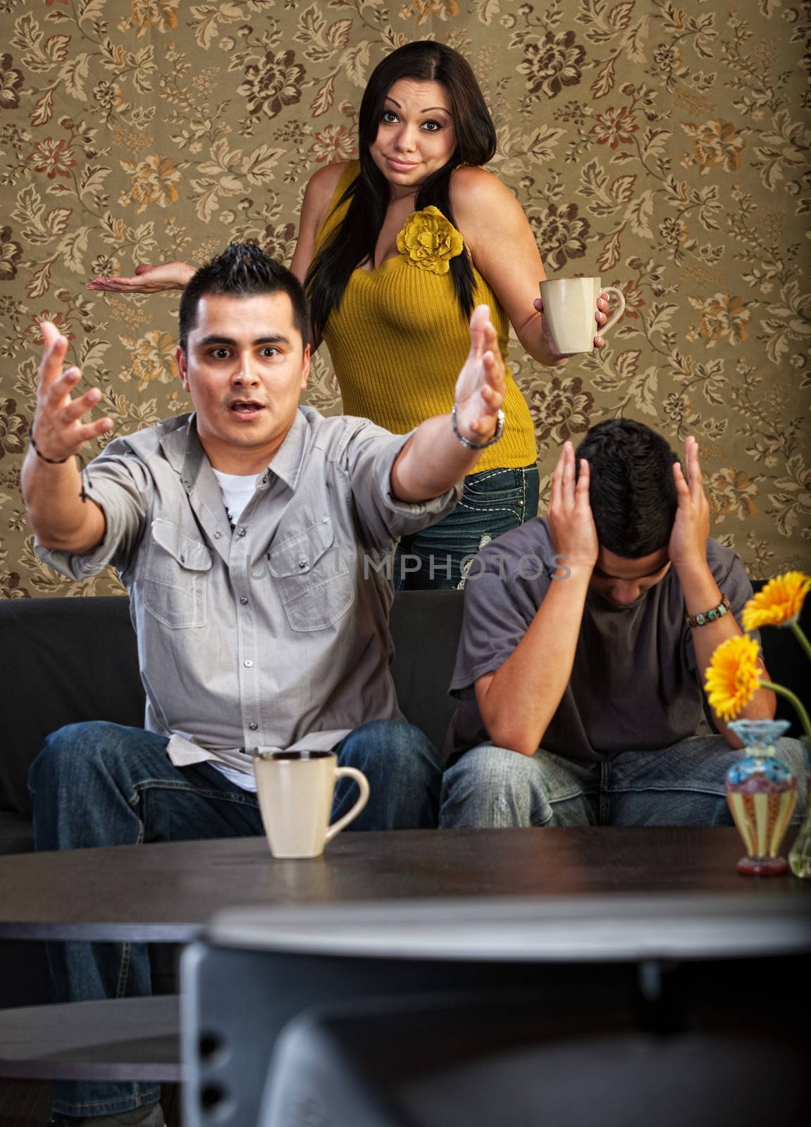 Frustrated Latino family indoors in front of television together
