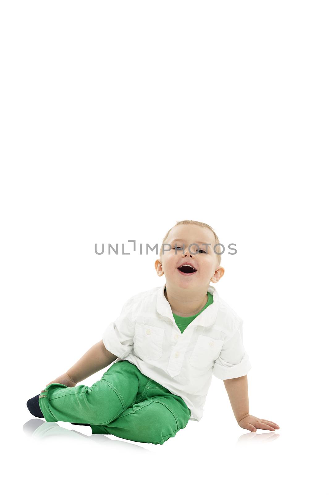 Cute little boy sitting comfortably on a white studio floor with his head tilted back laughing heartily