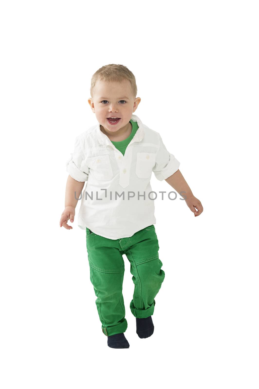Handsome little blond boy approaching the camera walking in mid stride with a cheerful friendly smile isolated on white