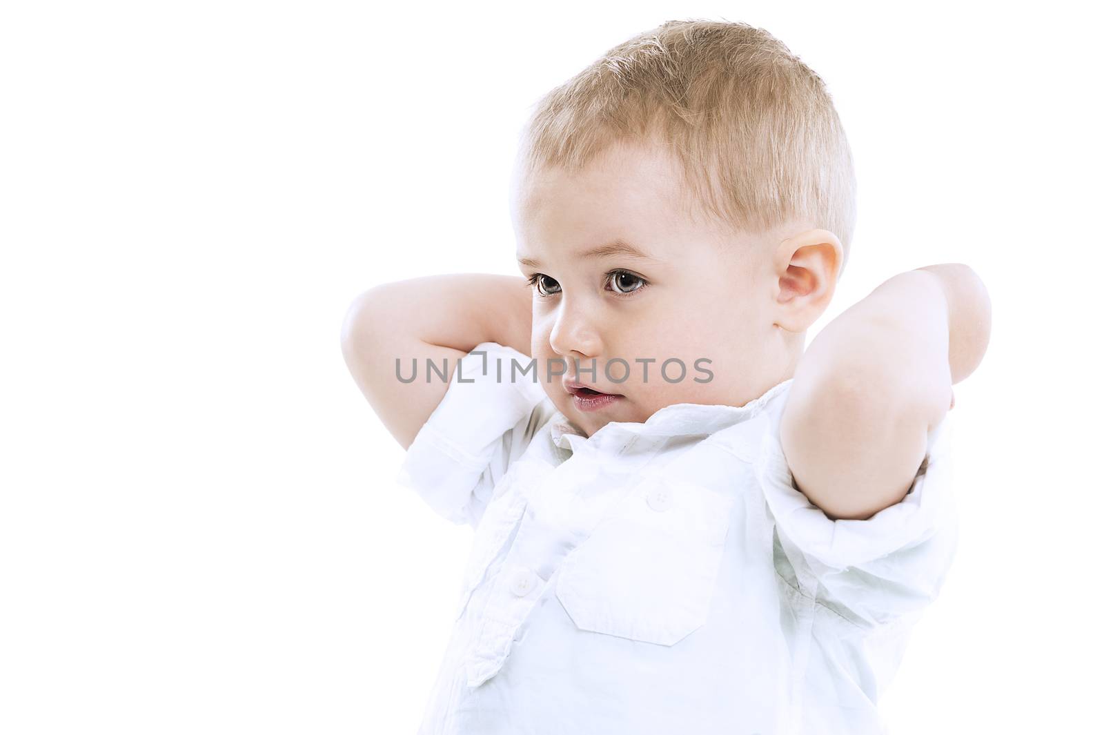 Handsome small boy with raised arms wearing a white shirt standing sideways looking towards the left of the frame, isolated on white