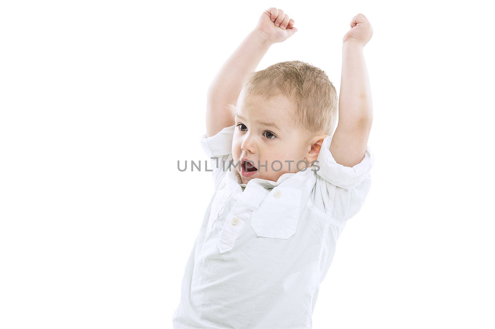 Excited playful handsome little boy standing with raised arms and his mouth open as though cheering isolated on a white background