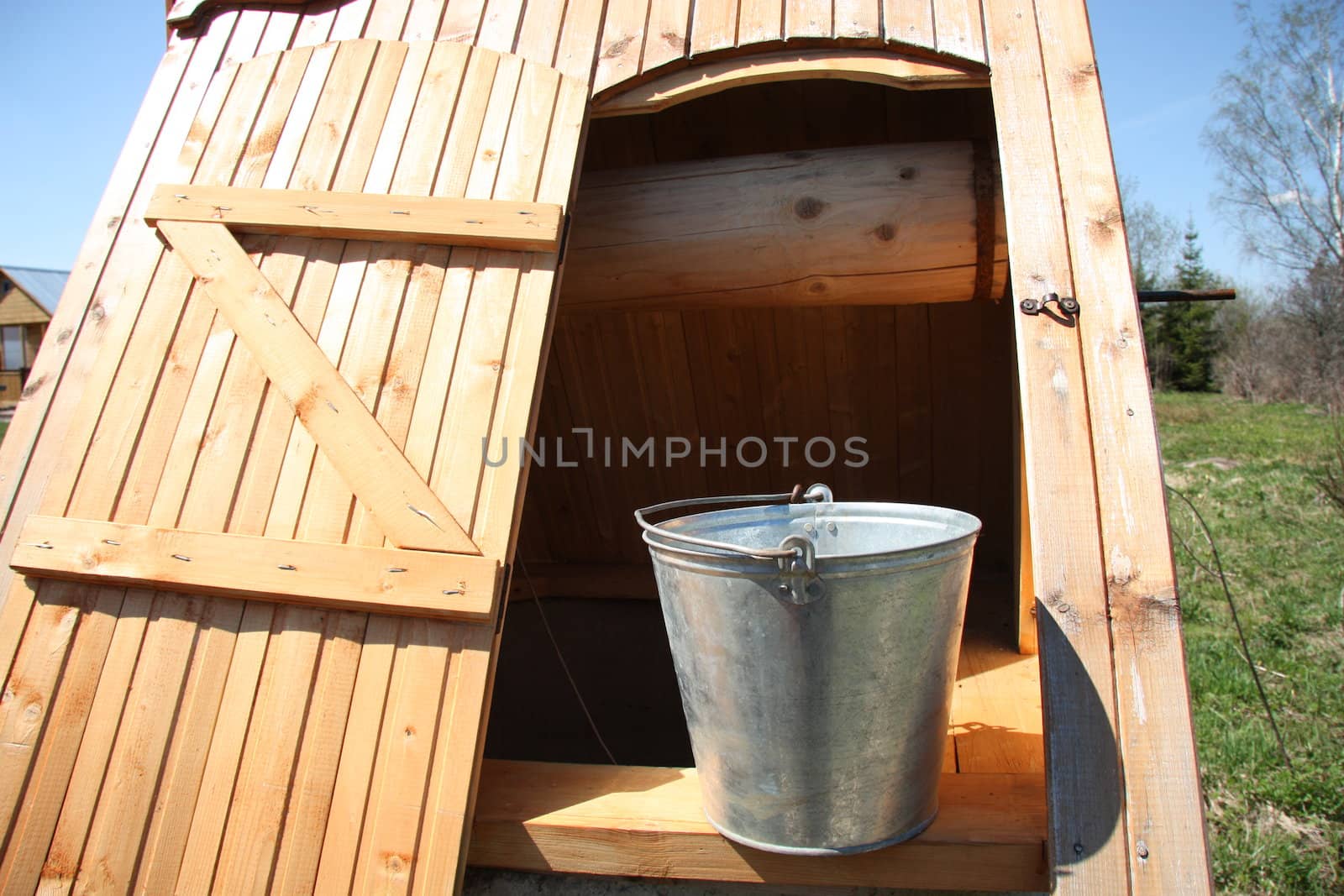 Vintage wooden well with a bucket in the summer in the countryside