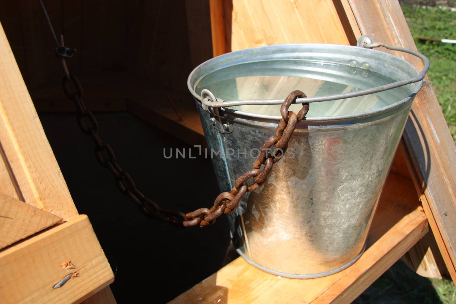 Vintage wooden well with a bucket of water in the summer in a countryside