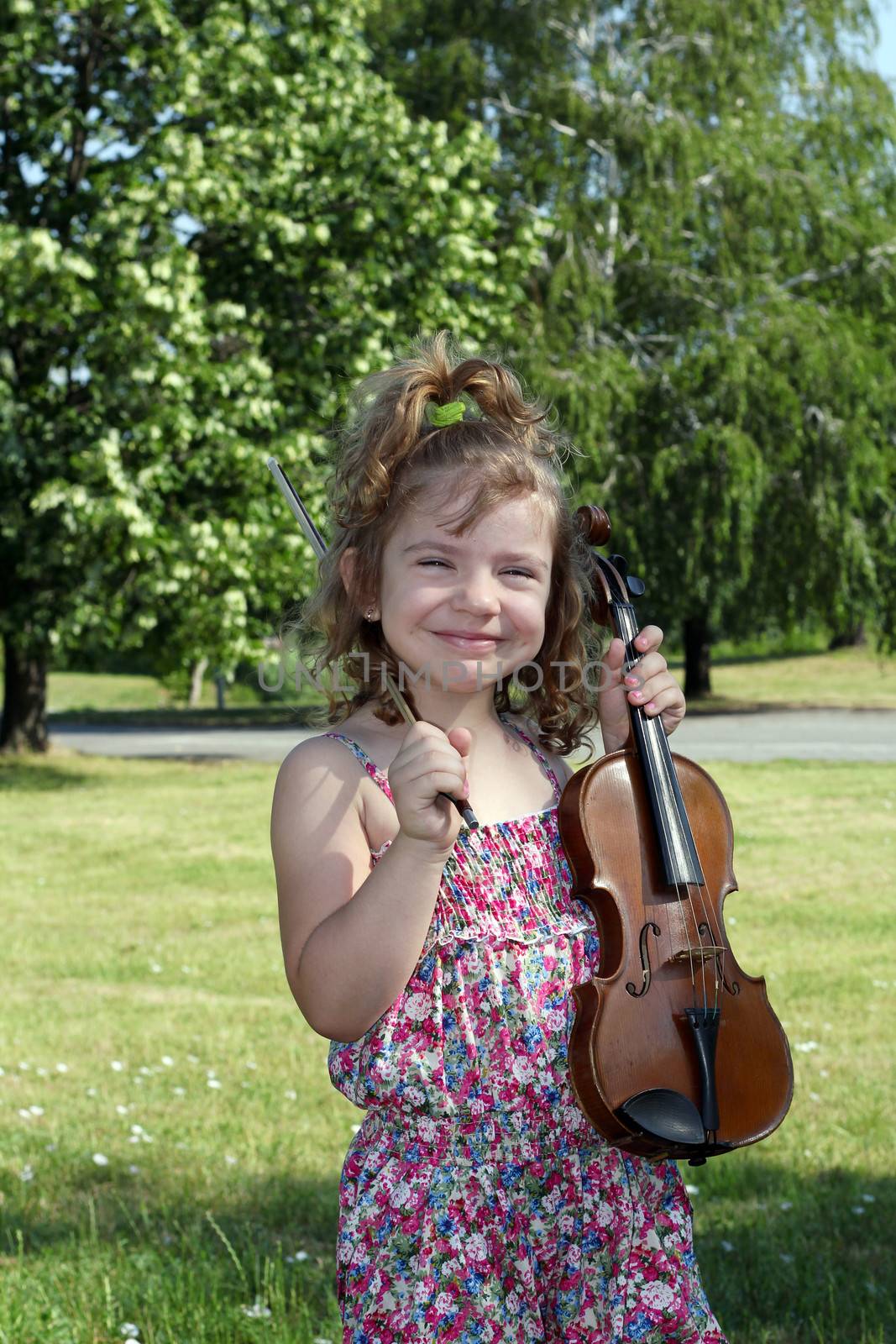 happy little girl with violin in park by goce