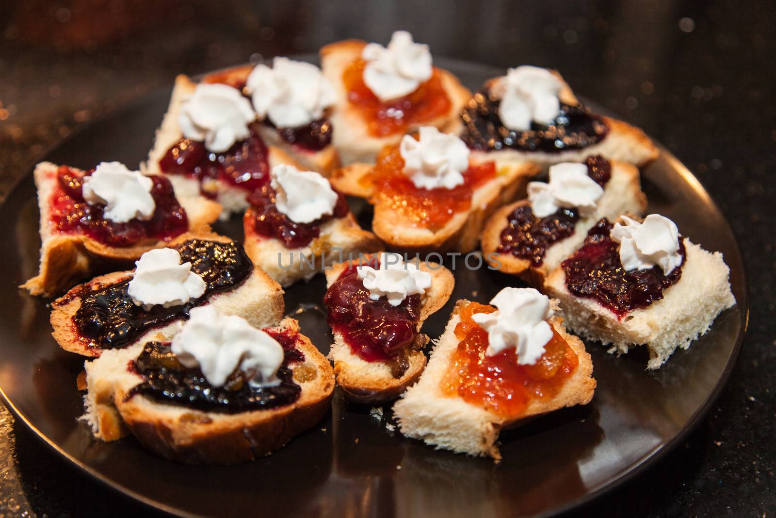 Bread pieces with marmalade and whipping cream on a plate