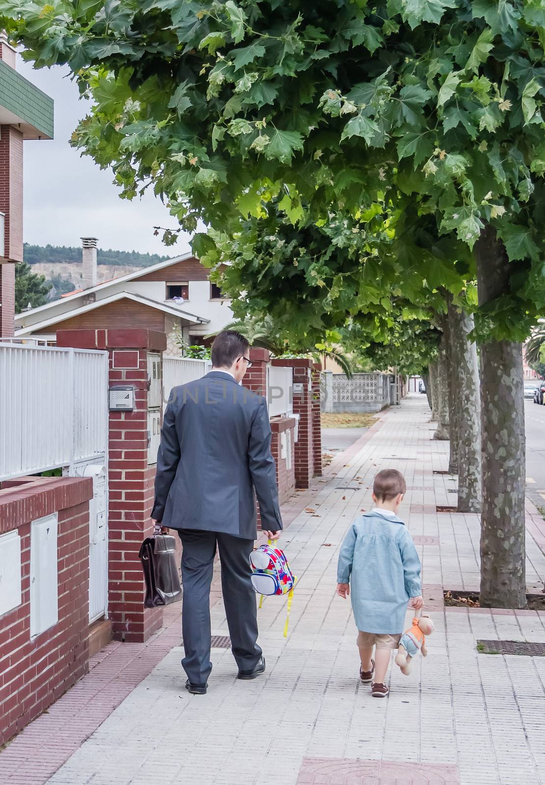 Business father and little cute son walking on the street to the school