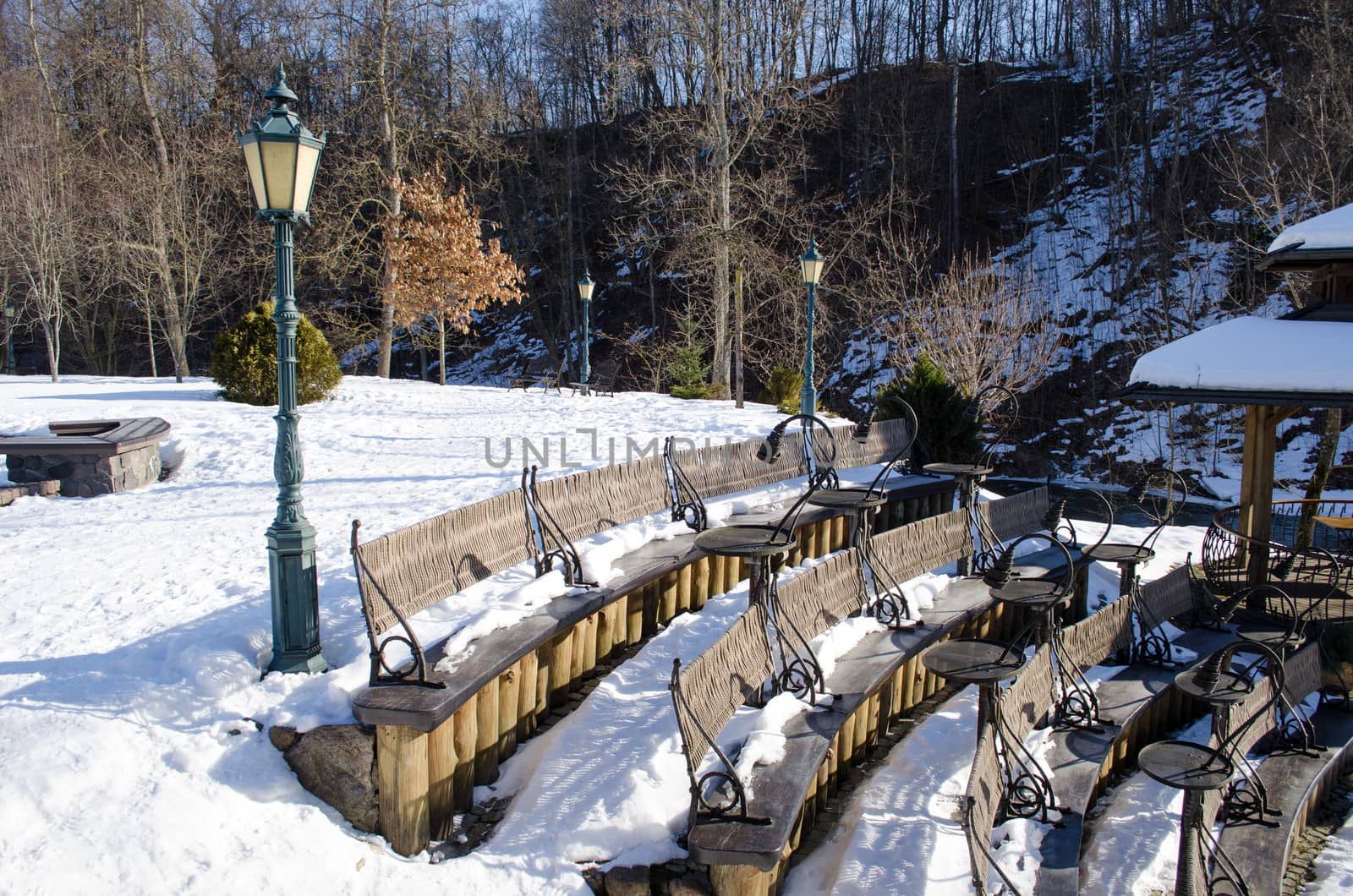 modern design seats and tables covered with snow in outside restaurant cafe in winter park.