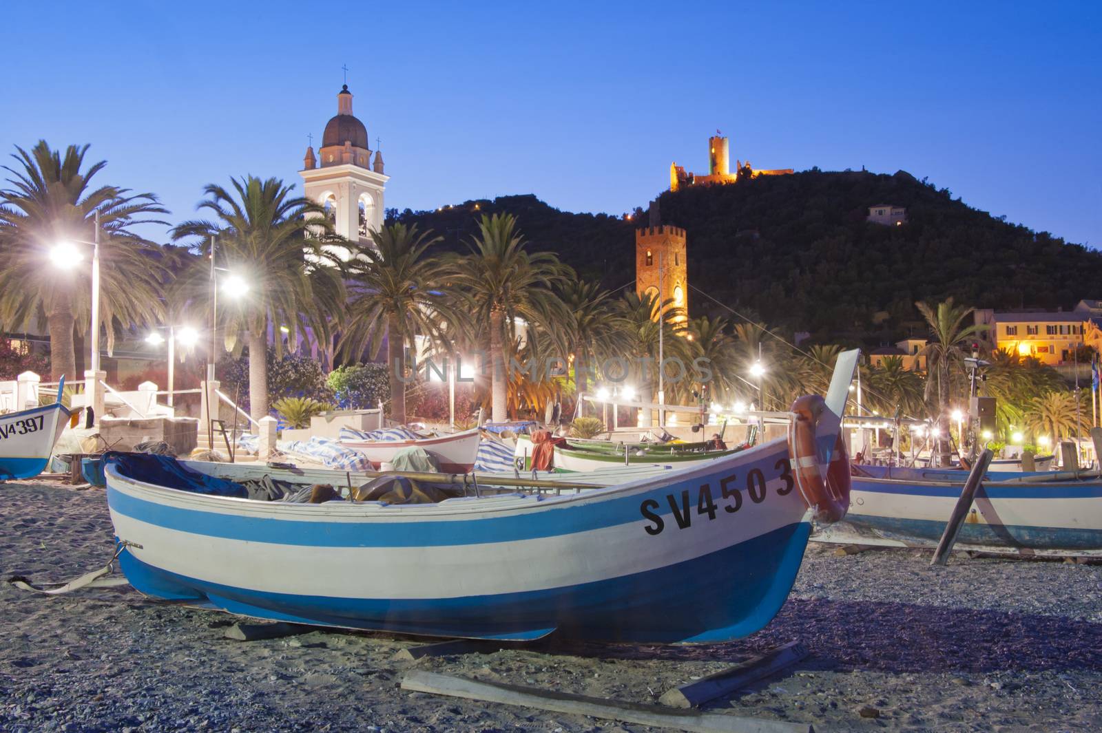 Boat on the cobblestones beach of Noli, facing the village of Noli, during the sunset