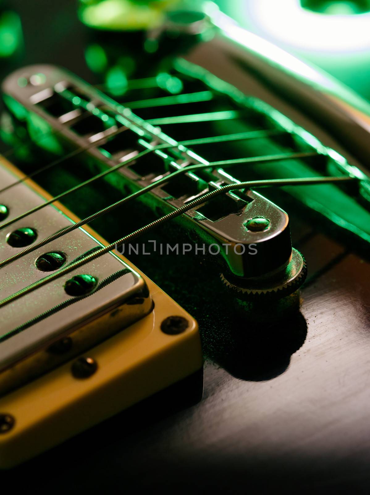 Macro abstract photo of the pickup, bridge and strings of an electric guitar. Shallow depth of field with focus on the first string.
