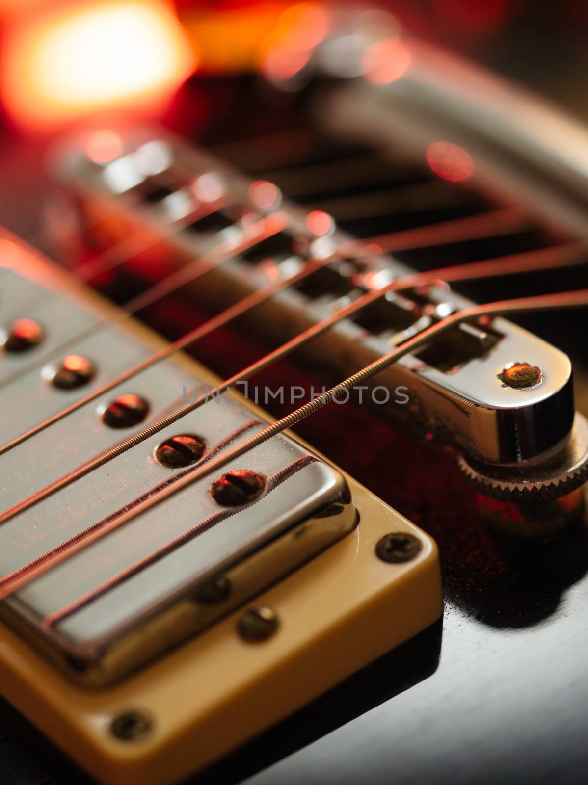 Macro abstract photo of the pickups, bridge and strings of an electric guitar. Shallow depth of field with focus on the first string.