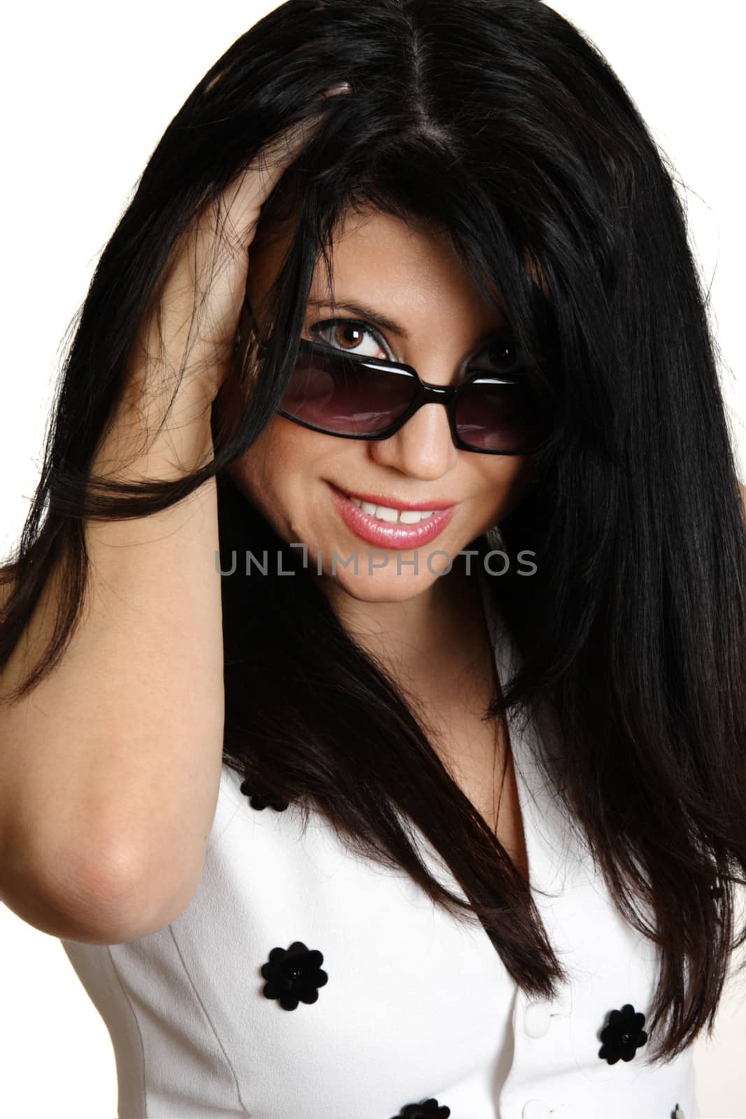 Beautiful young brunette woman smiling and looking over her sunglasses.  She has thick long black hair.  Feeling fabulous.  Fashion beauty, white background.