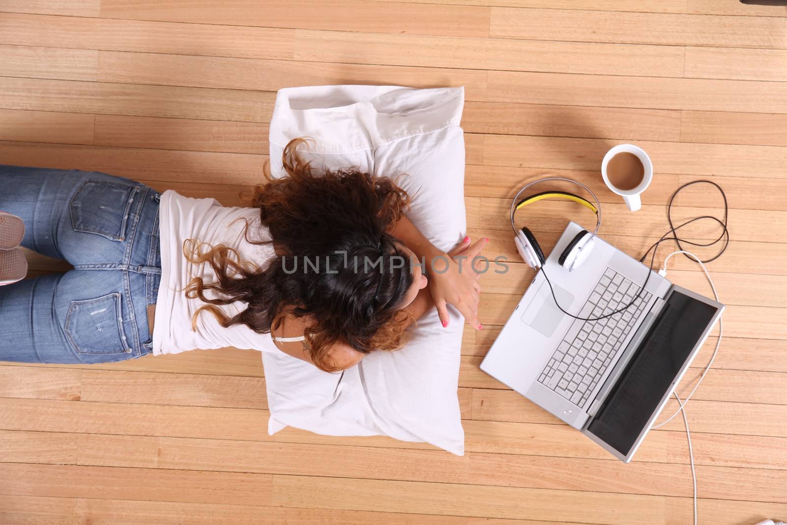 A girl laying on the Floor while surfing on the Internet with a Laptop.