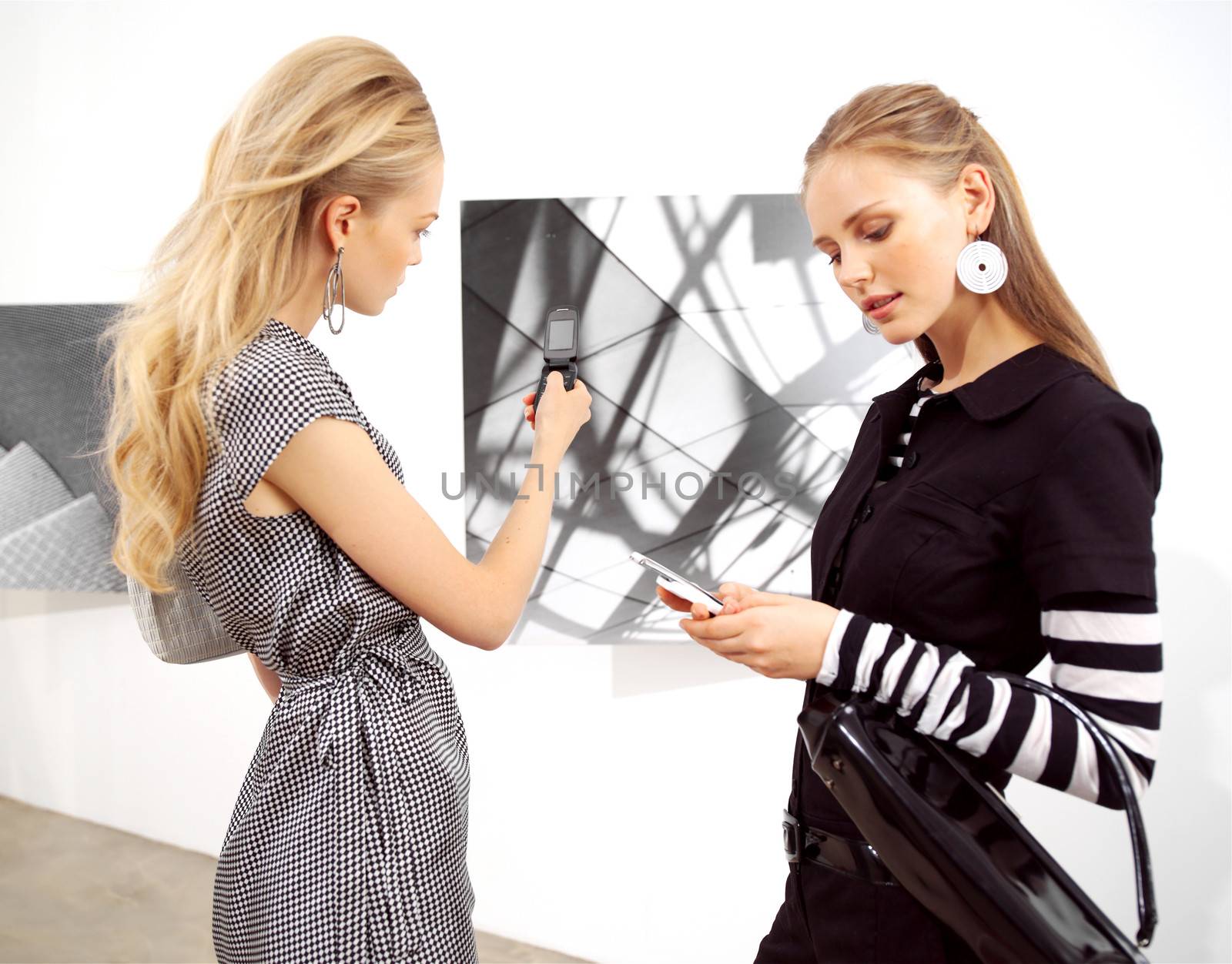 girl-friend with mobile phones at an exhibition 