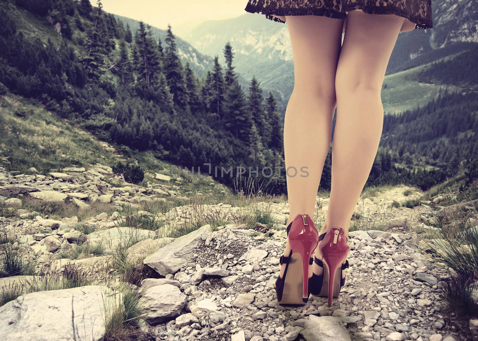 Concept with a women trying to climb down a mountain in elegant shoes