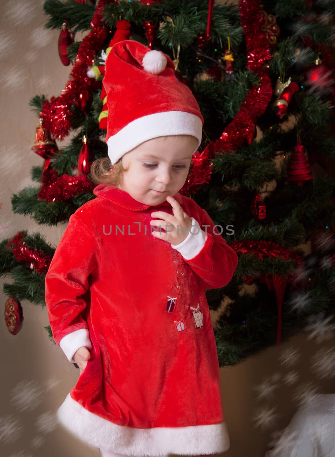 Adorable little girl putting wishes under Christmas tree
