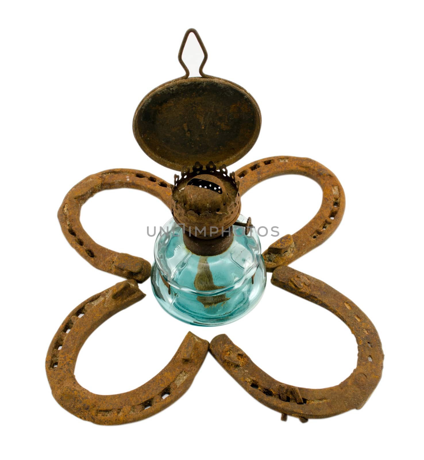 retro kerosene lamp in center of clover made of rusty horse shoes isolated on white background.