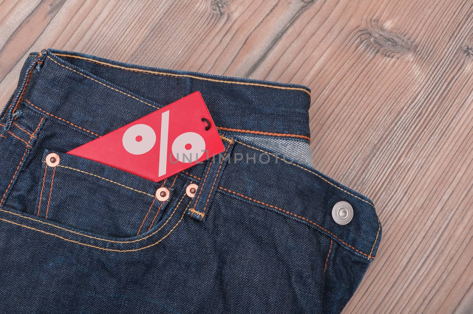 Red Sale Tag With Percentage Symbol in Pocket of Blue Jeans - With Copyspace