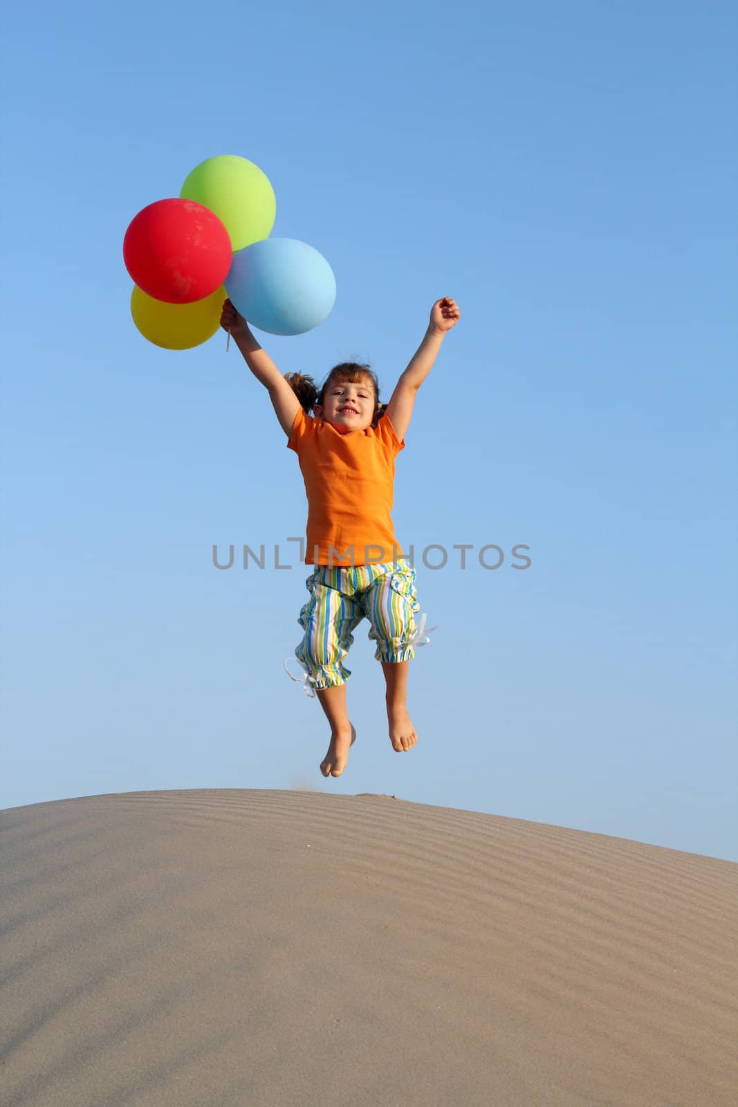 happy little girl jump on sand dune