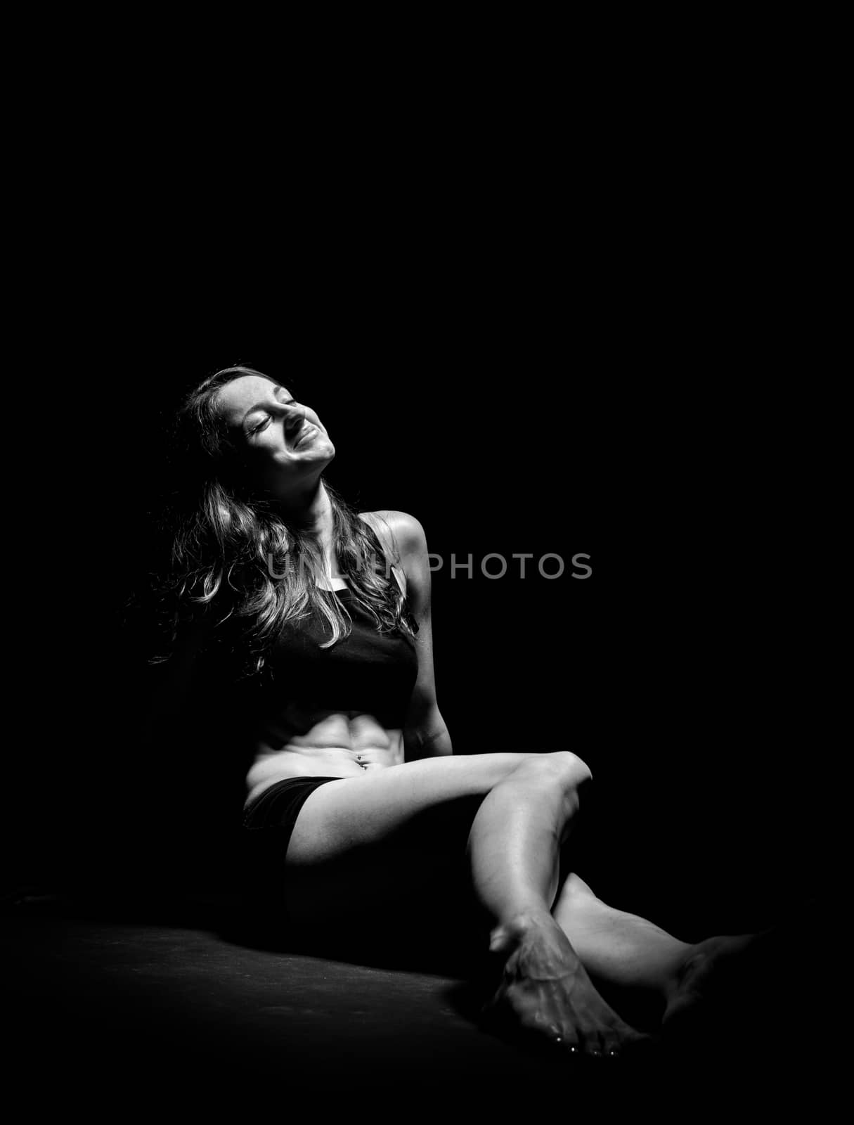 Young muscular woman under bright light in a studio