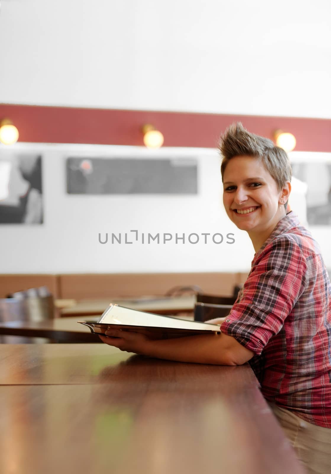 Young happy woman in a restaurant reading the menu