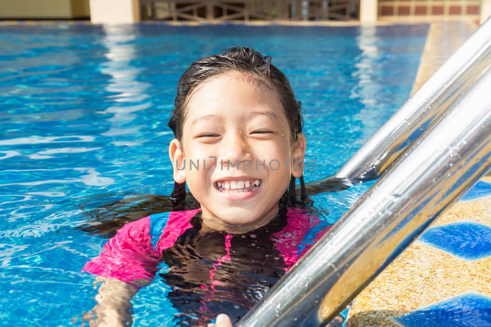 Girl relaxing on the side of a swimming pool