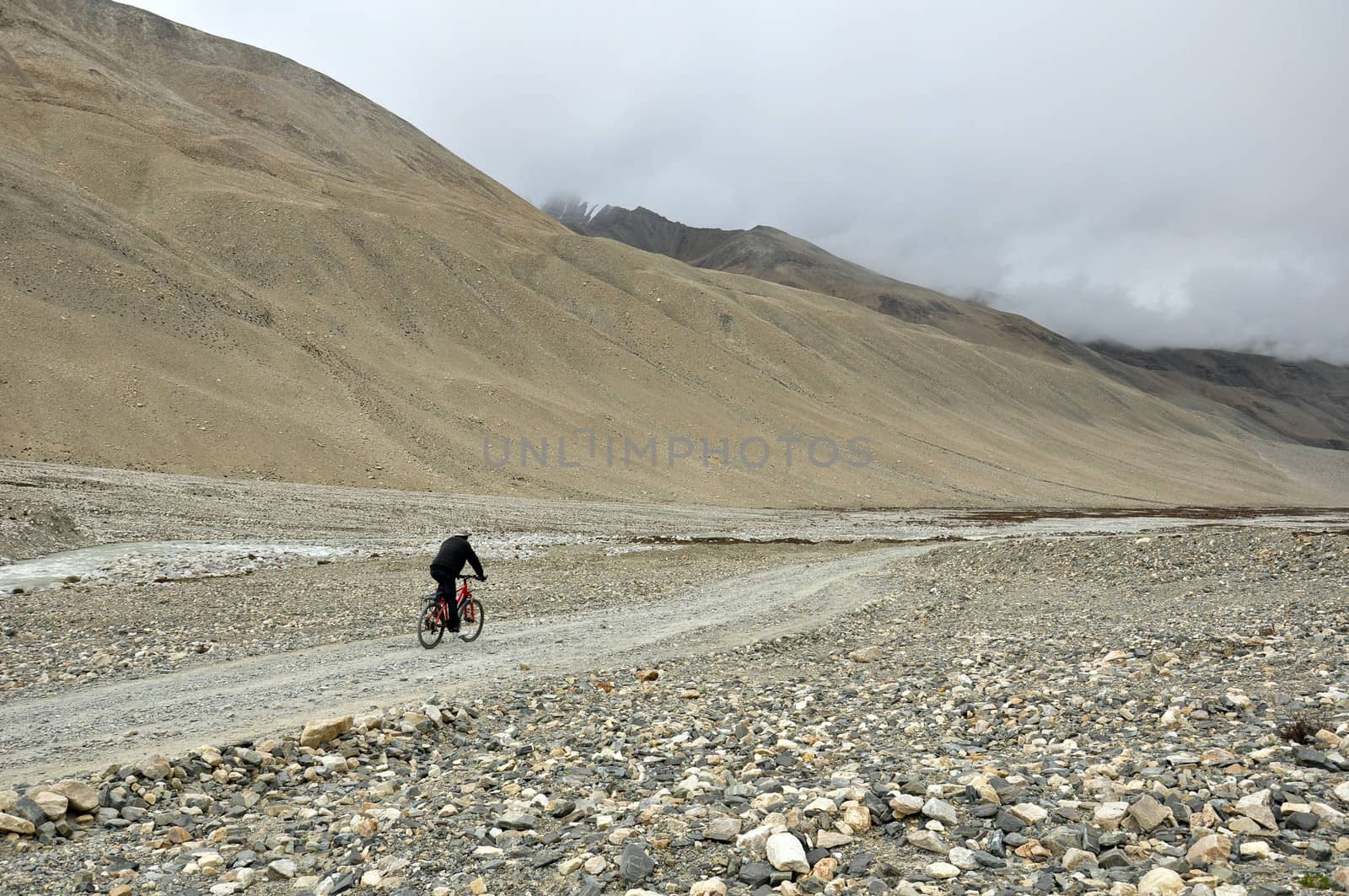 an old man is cycling along the track in the mount everest track in Tibet