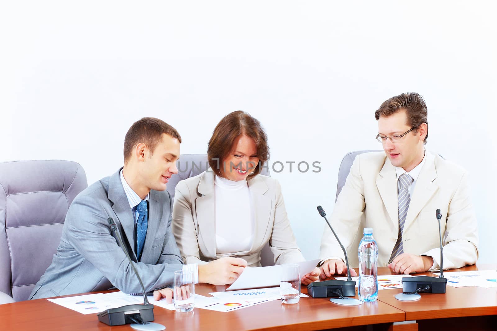 Image of three businesspeople sitting at table at conference