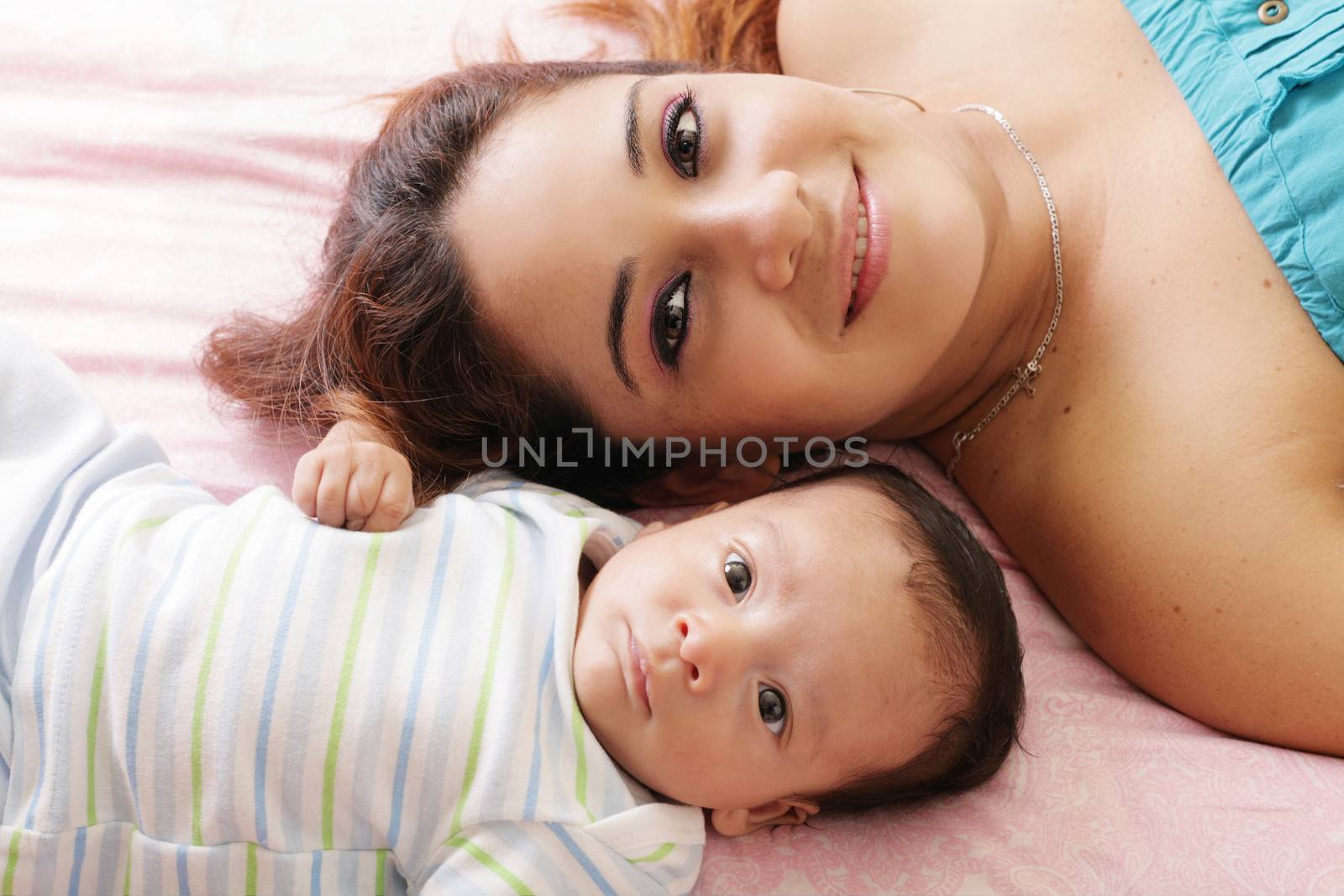 Portrait of happy young attractive hispanic mother lying with he by dacasdo