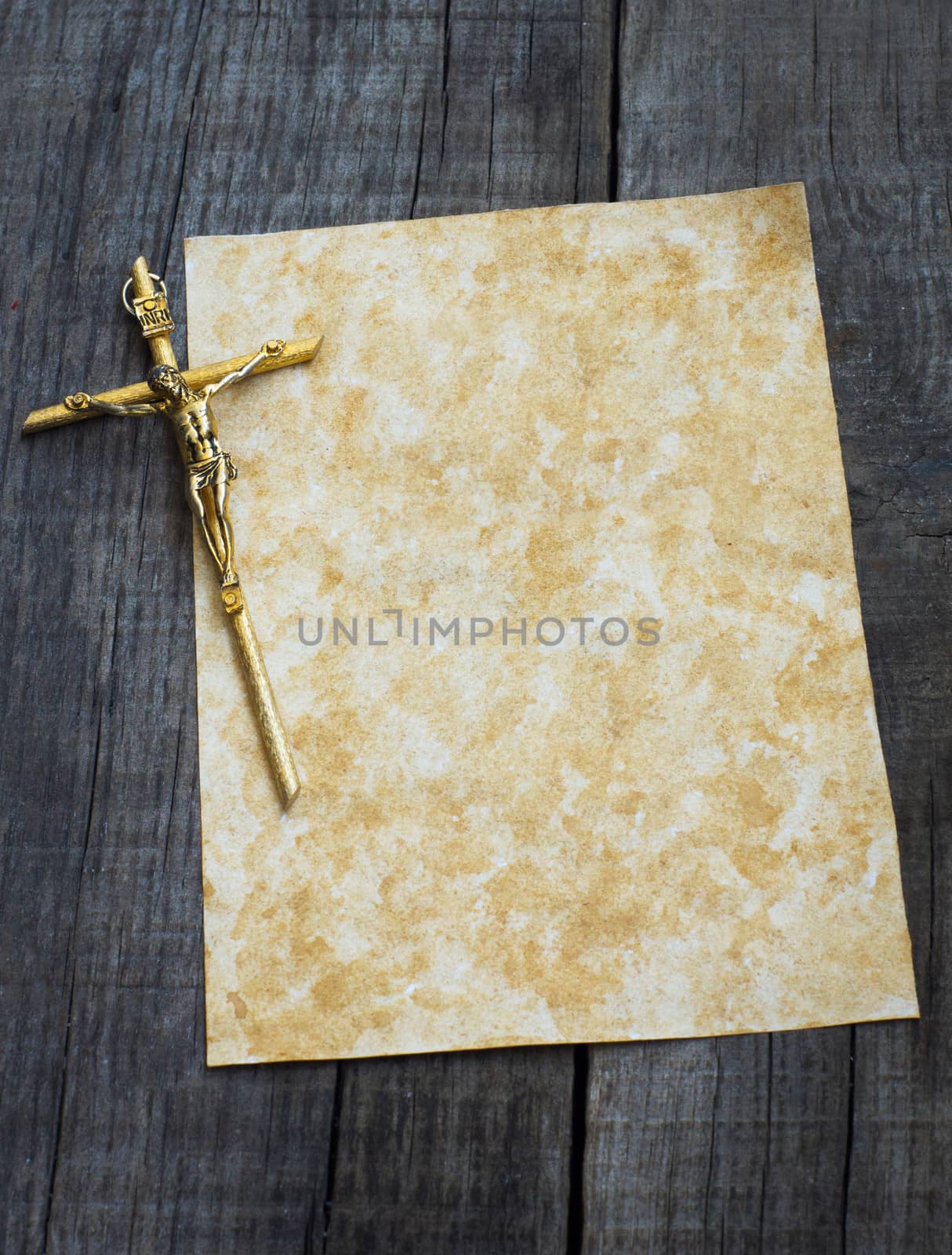 A stained paper with a Crucifix on wooden background