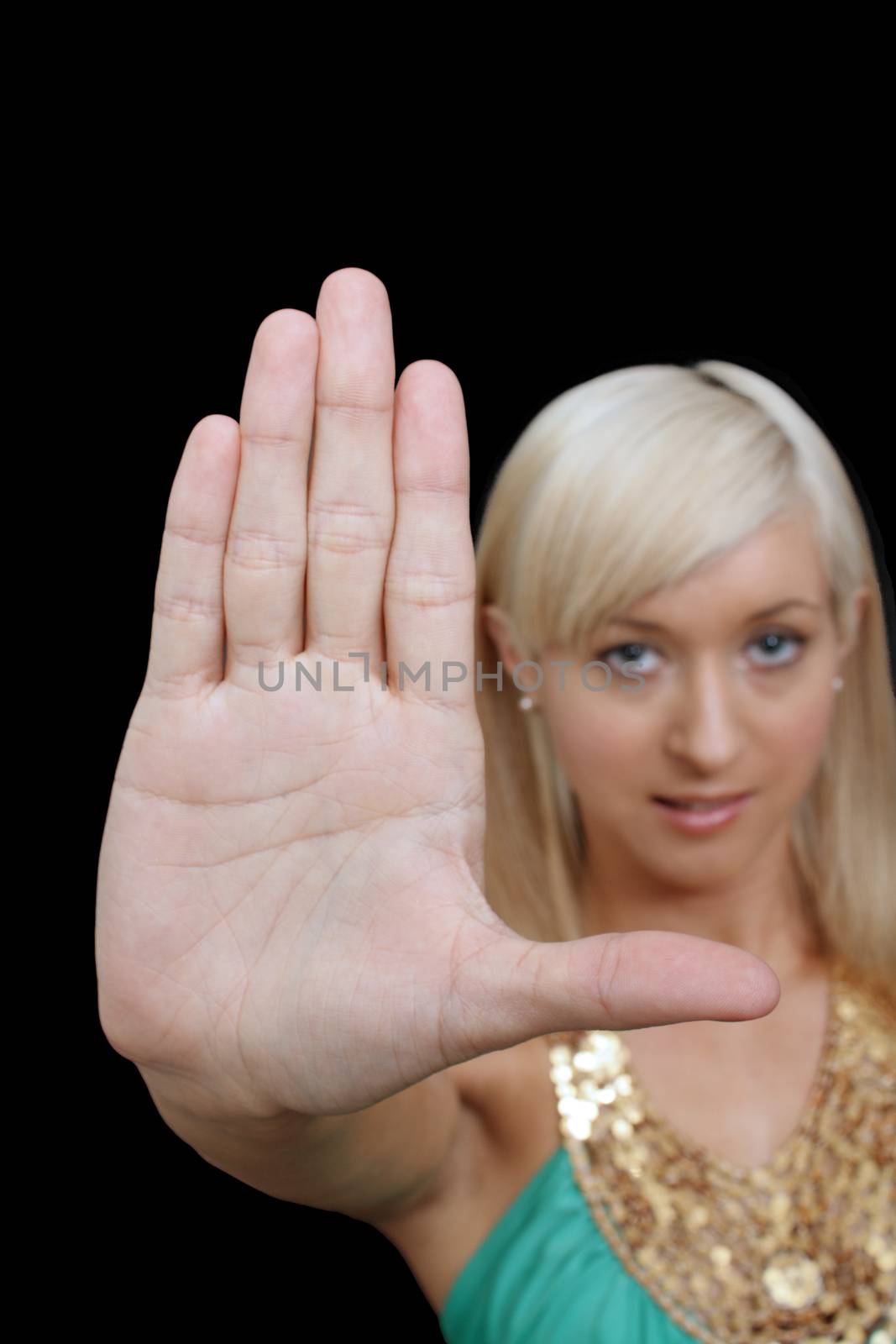 A lovely young blonde puts her hand to the camera, palm flat.  Selective focus on her hand.