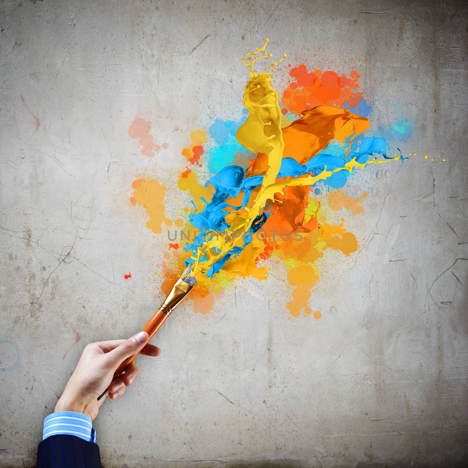 Close-up of human hand holding paint brush making colorful paint splashes