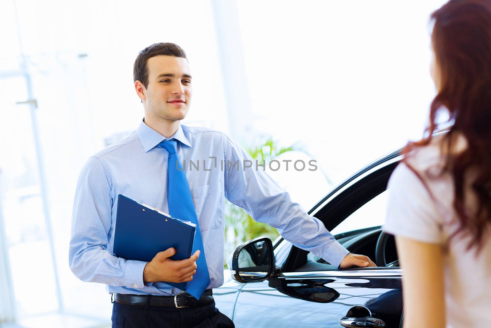 Attractive woman at car salon with consultant choosing a car